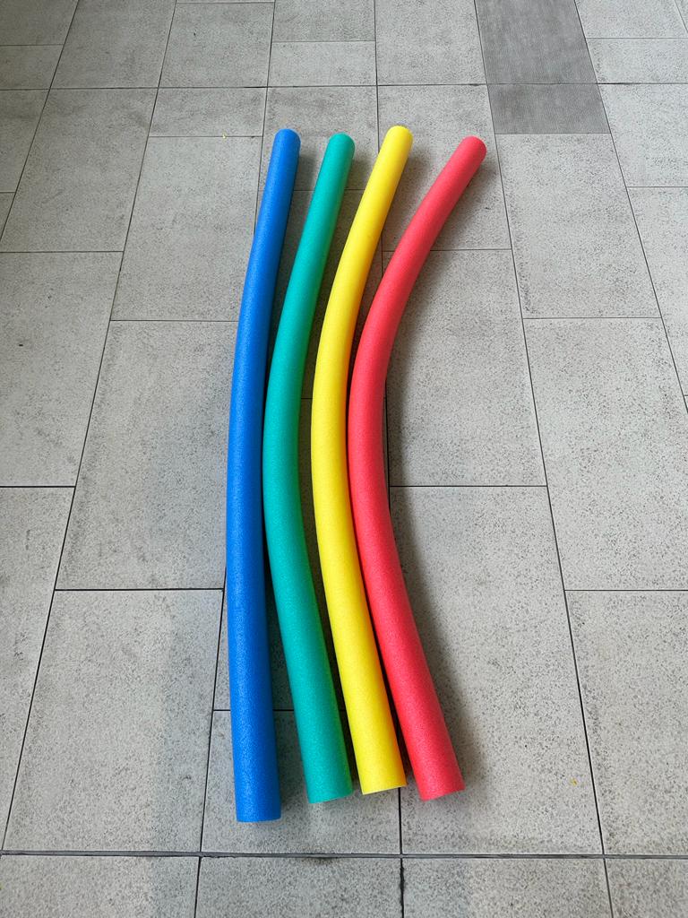 Brightly colored pool noodles arranged poolside, ready to assist in a children's swimming class.