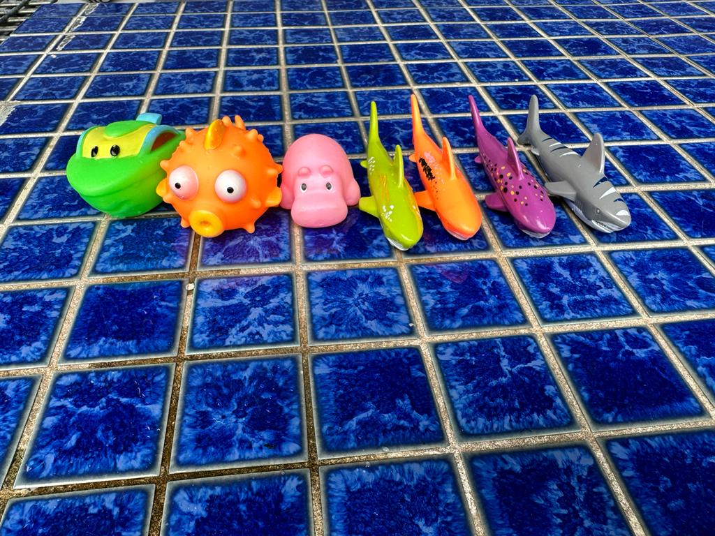 Assorted bright floater and sinker toys scattered in a swimming pool, ready to enhance children's swimming lessons with fun and educational play.