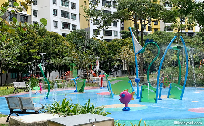 A water play area designed like a ship outline featuring a ship steering wheel, a sea snake, and a fish sprouting water.