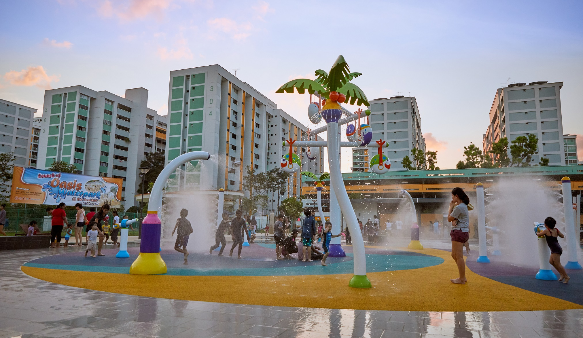 Yishun-based water play zone featuring a cascading water curtain and life-sized board game elements, with nearby vending machines for refreshments.